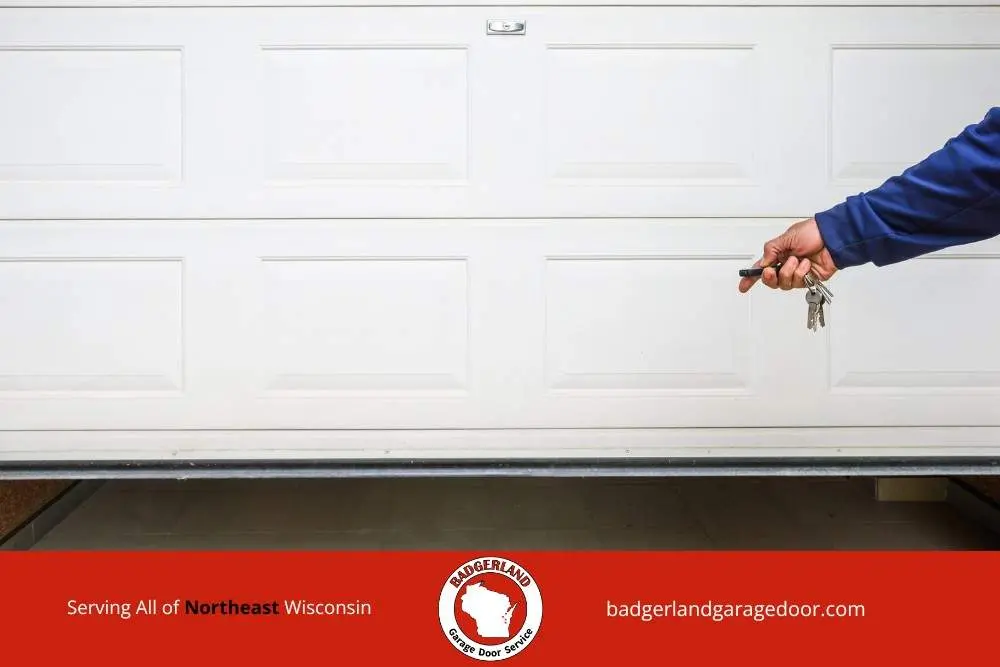 Hand holding remote near a garage door as Bestland Garage Door provides weatherproofing service for Wisconsin homes in cold weather.
