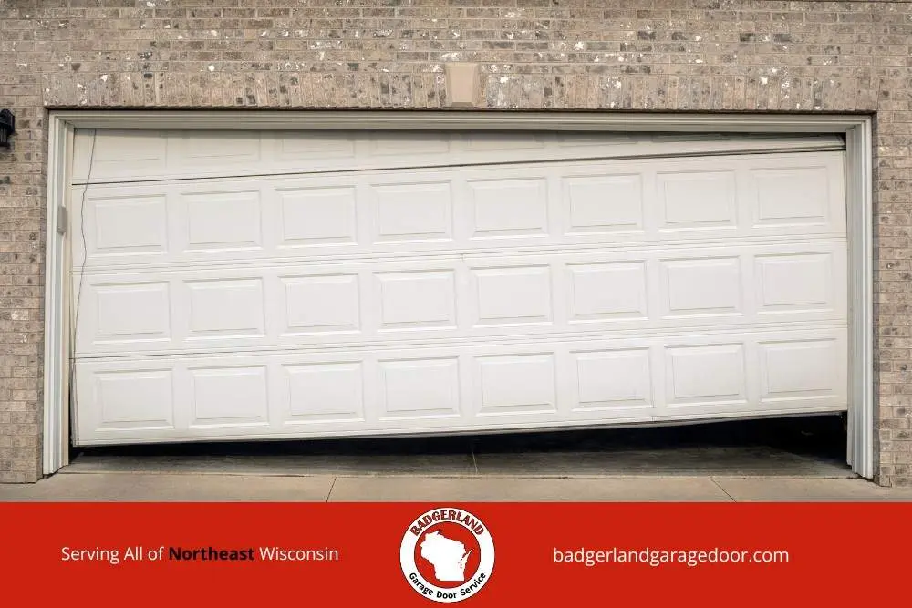 Winter damaged garage door off track at a Wisconsin home, showing issues Bestland Garage Door provides service to repair.