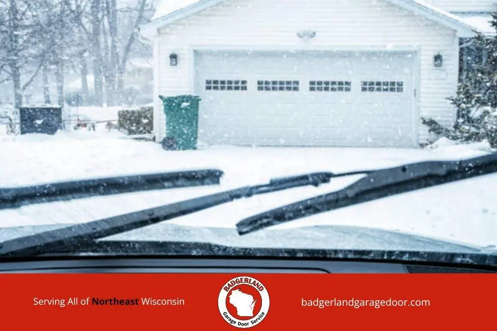 Snow covered driveway and garage in Wisconsin, highlighting winter strain on doors that Bestland Garage Door provides service to fix.