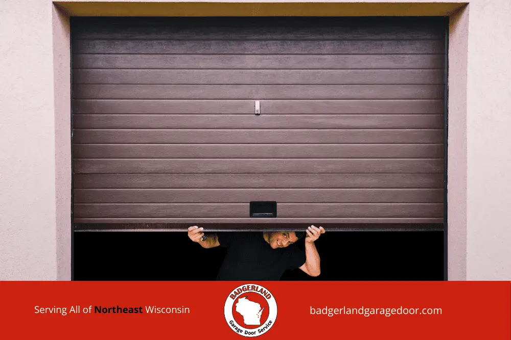 Why Garage Door Balance Matters More in Wisconsin Winters-1 A person peeks under a brown garage door, showcasing Garage Door Repair services in Wisconsin.| Bestland Garage Door Service – Green Bay & Appleton Garage Door Repair