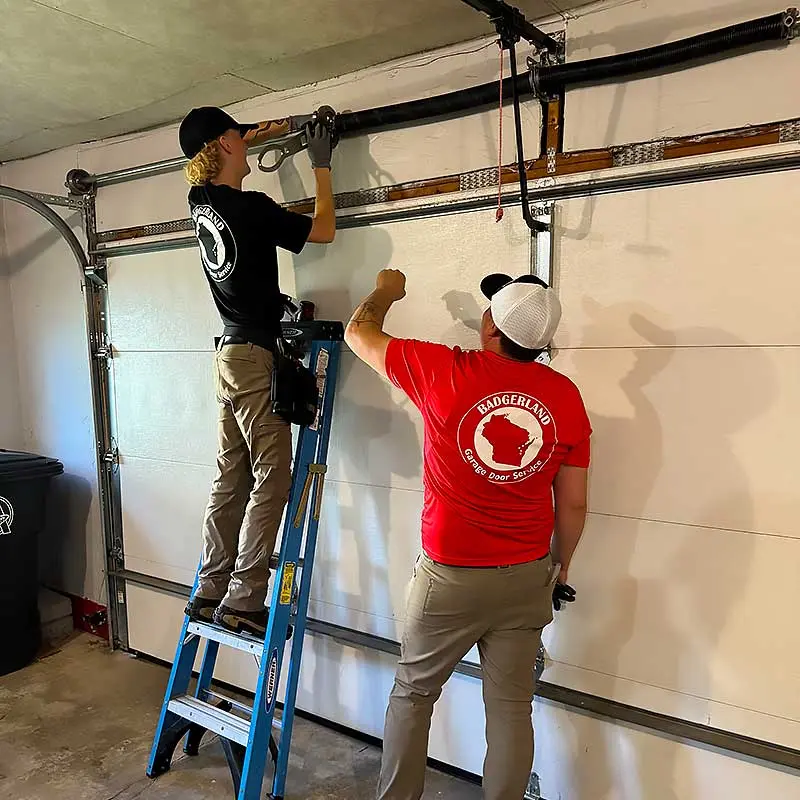 Two technicians in Bestland shirts repairing a garage door in Appleton.| Bestland Garage Door Service – Green Bay Garage Door Repair