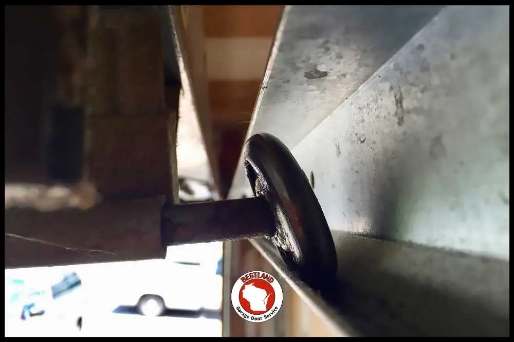 Close-up of a garage door roller in its metal track, highlighting the mechanics of garage door repair. The Bestland Garage Door Service logo is visible, emphasizing expert repair services in Green Bay and Appleton.| Bestland Garage Door Service – Green Bay Garage Door Repair